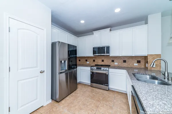 a kitchen with stainless steel appliances granite countertop a refrigerator stove and sink