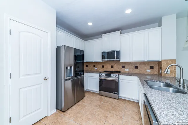 a kitchen with stainless steel appliances granite countertop a refrigerator stove and sink