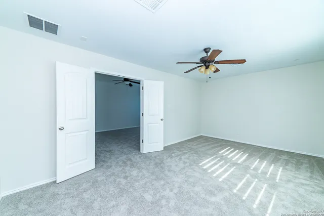 an empty room with a ceiling fan and window