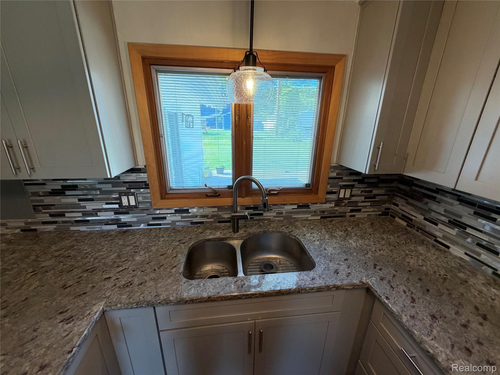 14629 Newburgh Road Livonia, MI 48154 - Photo 6 of 27 Dual stainless steel sink with a gooseneck faucet, light-toned cabinetry, multi-toned glass tile backsplash, and a pendant light fixture