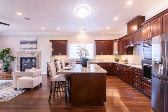a living room with couches and kitchen view with wooden floor