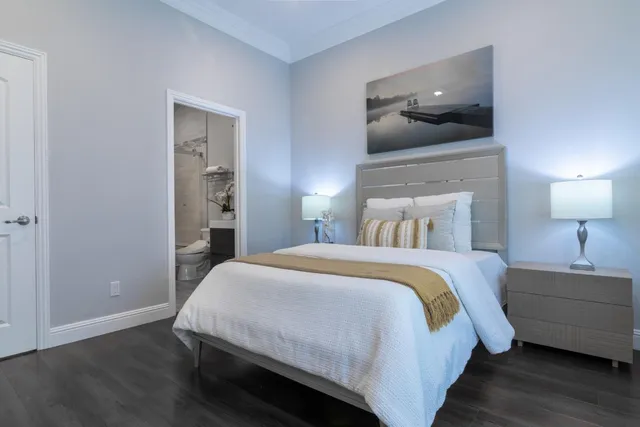 a view of a white house with a large tree and wooden fence