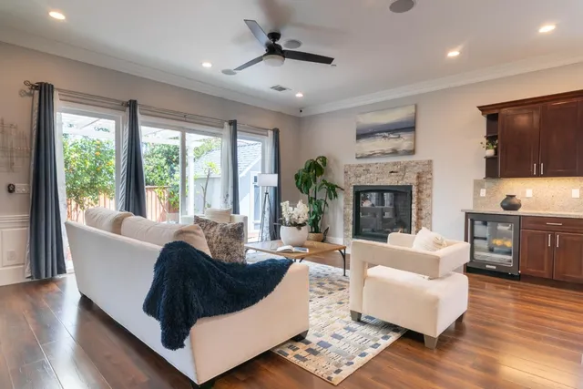 a kitchen with stainless steel appliances kitchen island granite countertop a refrigerator a stove a sink a dining table and chairs with wooden floor