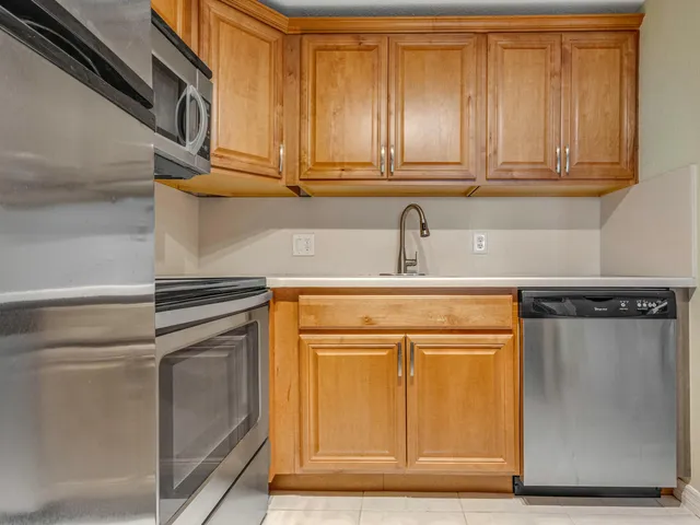 a kitchen with stainless steel appliances granite countertop a sink and a refrigerator