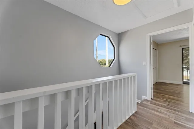 a view of a hallway with wooden floor and a mirror