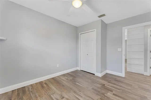 a view of an empty room with wooden floor and closet