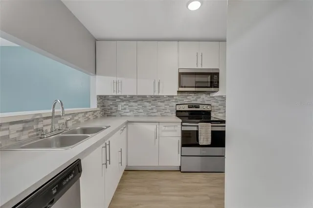 a kitchen with sink a microwave and cabinets