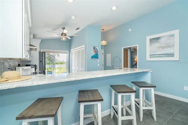 a kitchen with granite countertop white cabinets and chairs