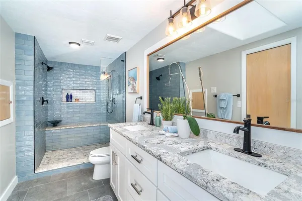 a bathroom with a granite countertop sink a toilet and shower