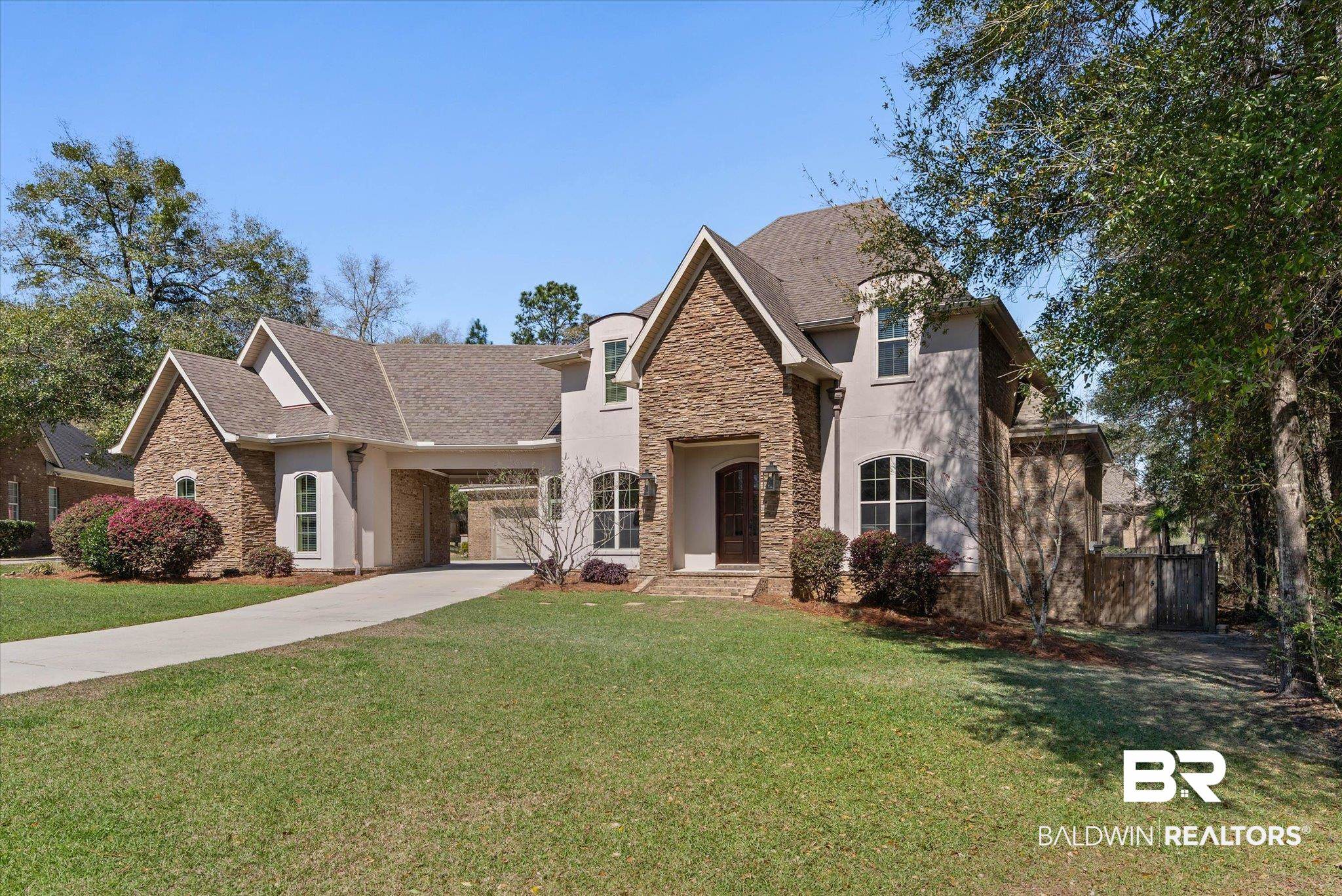French country inspired facade featuring stone siding, concrete driveway, stucco siding, and a shingled roof