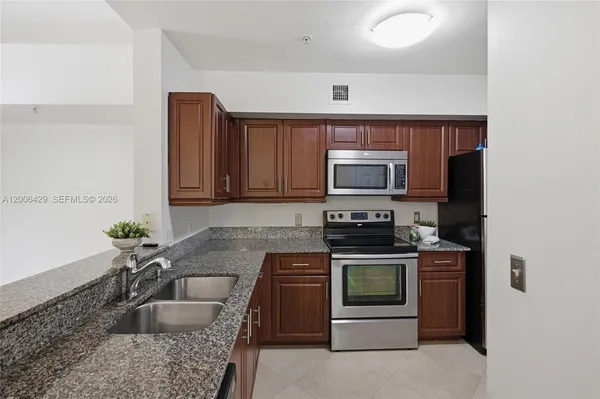 a kitchen with granite countertop a stove sink and microwave