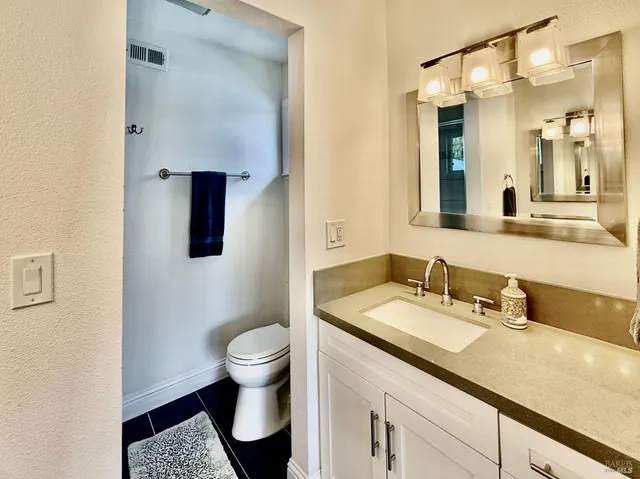 a bathroom with a granite countertop sink a toilet and a mirror