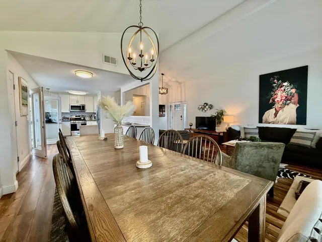 a dining room with wooden floor a chandelier a wooden table and chairs