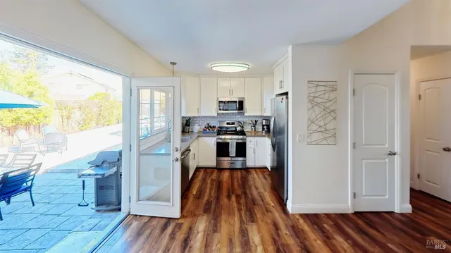 a kitchen with a refrigerator and wooden floor