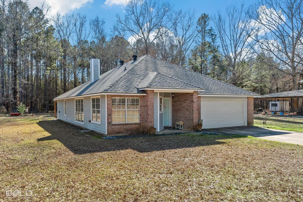 136 Scarborough Road Benton, LA 71006 - Photo 27 of 32 Brick and siding exterior featuring a covered front entry, attached two-car garage, multiple pane windows, and a shingle roof