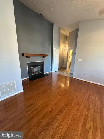 a view of an empty room with wooden floor fireplace and a window