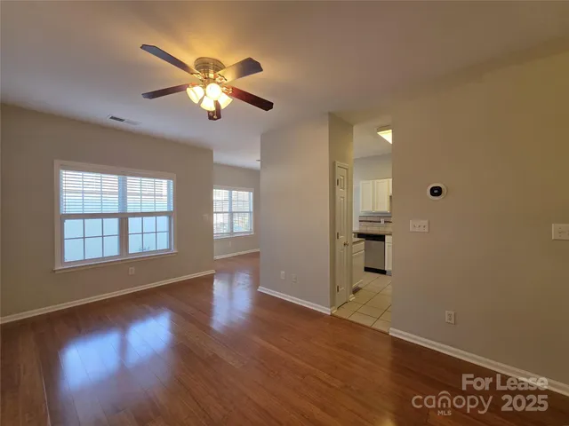 a view of an empty room with window and wooden floor