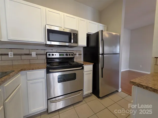 a kitchen with stainless steel appliances granite countertop a refrigerator stove and microwave