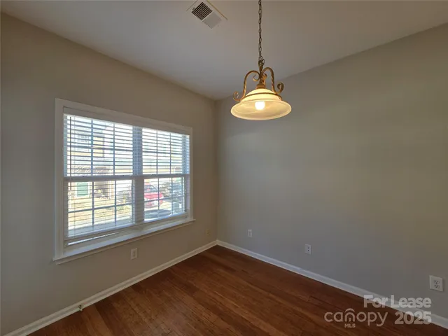a view of empty room with wooden floor and window