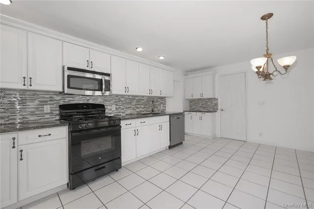 a kitchen with granite countertop white cabinets stainless steel appliances and a counter space