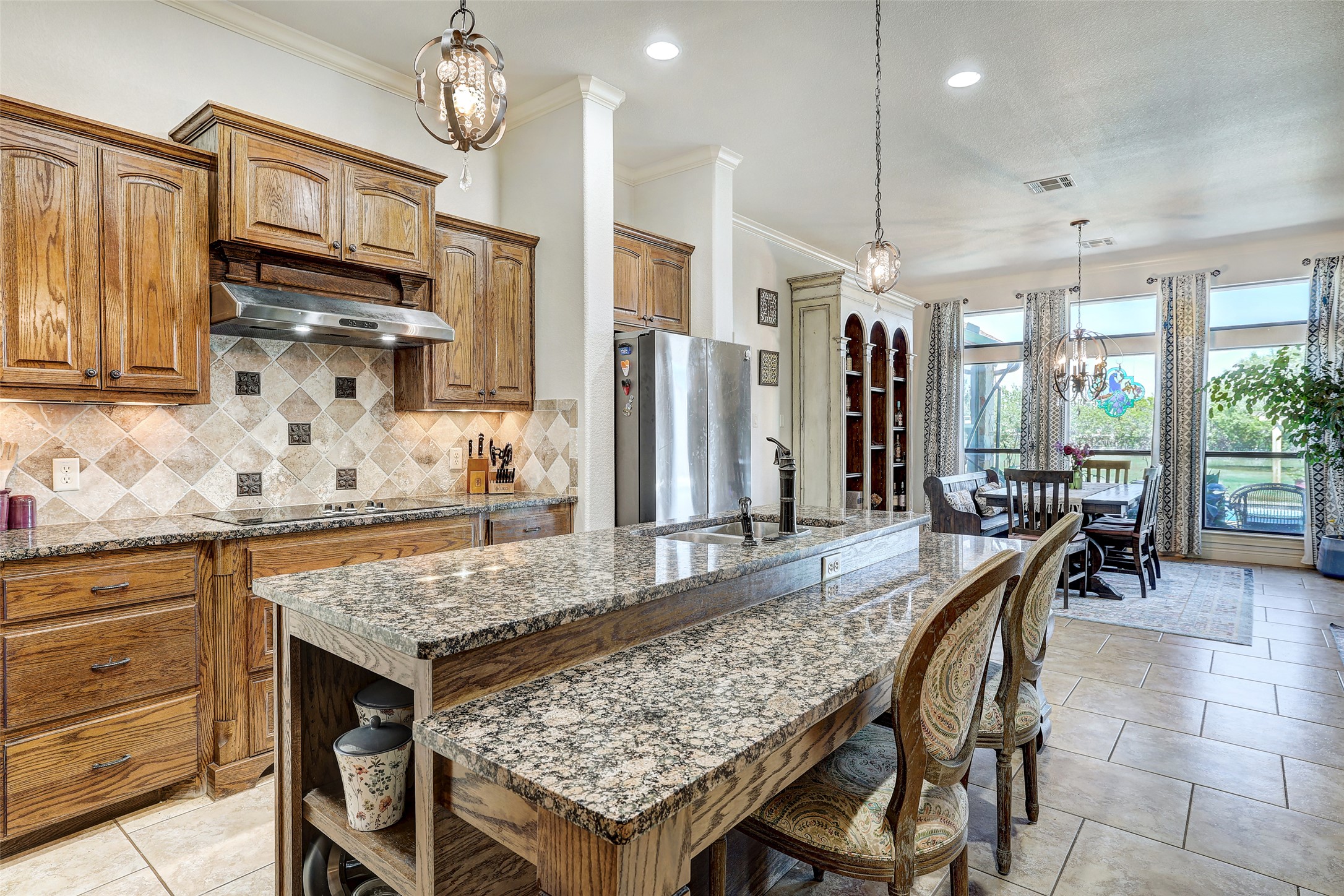 Undisclosed Address Georgetown, TX 78633 - Photo 19 of 39 Kitchen featuring a chandelier, brown cabinets, hanging light fixtures, dark stone counters, and ornamental molding