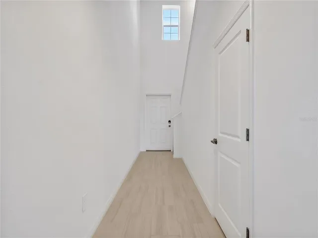 a view of a hallway with wooden floor and a white wall