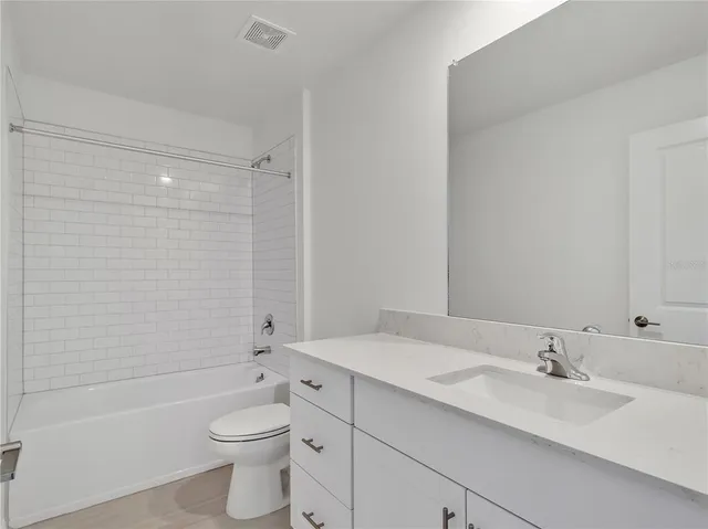 a bathroom with a bathtub shower sink mirror vanity and toilet