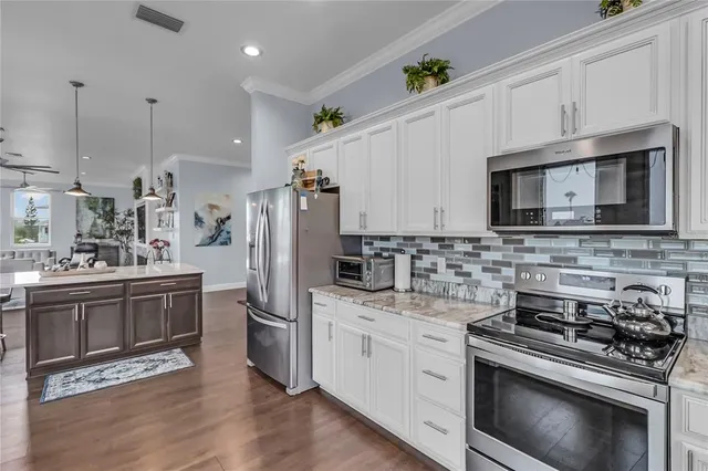 a kitchen with stainless steel appliances a stove a sink cabinets and a wooden floor