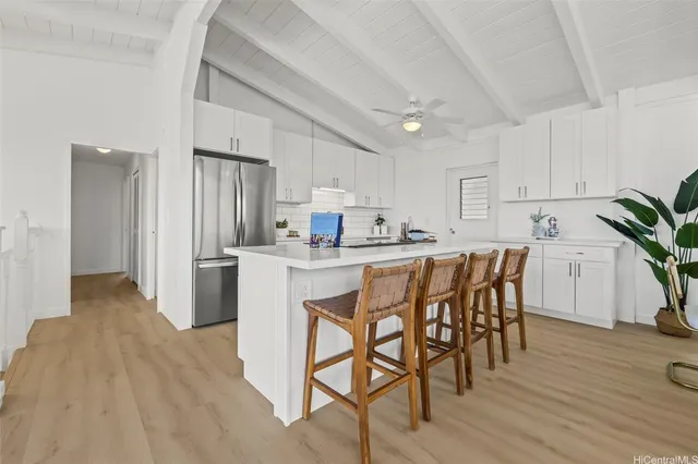 a kitchen with stainless steel appliances a dining table chairs stove refrigerator and cabinets