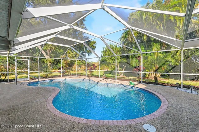 a view of a house with a big yard and palm trees