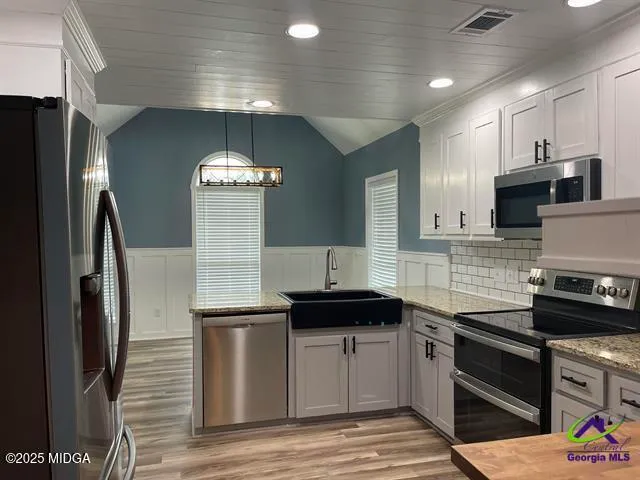 a kitchen with stainless steel appliances granite countertop a refrigerator a stove and a sink