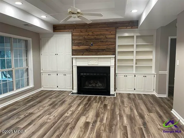 an empty room with wooden floor a fireplace and windows in a room