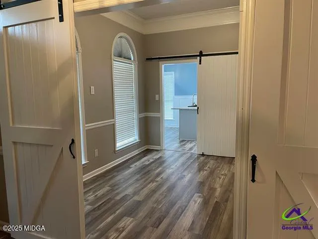 a view of a hallway with wooden floor and a bathroom