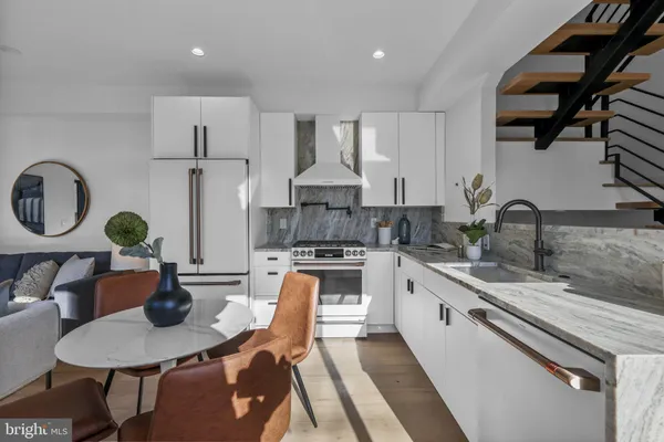 a kitchen with stainless steel appliances granite countertop a stove a sink dishwasher a dining table and chairs with wooden floor