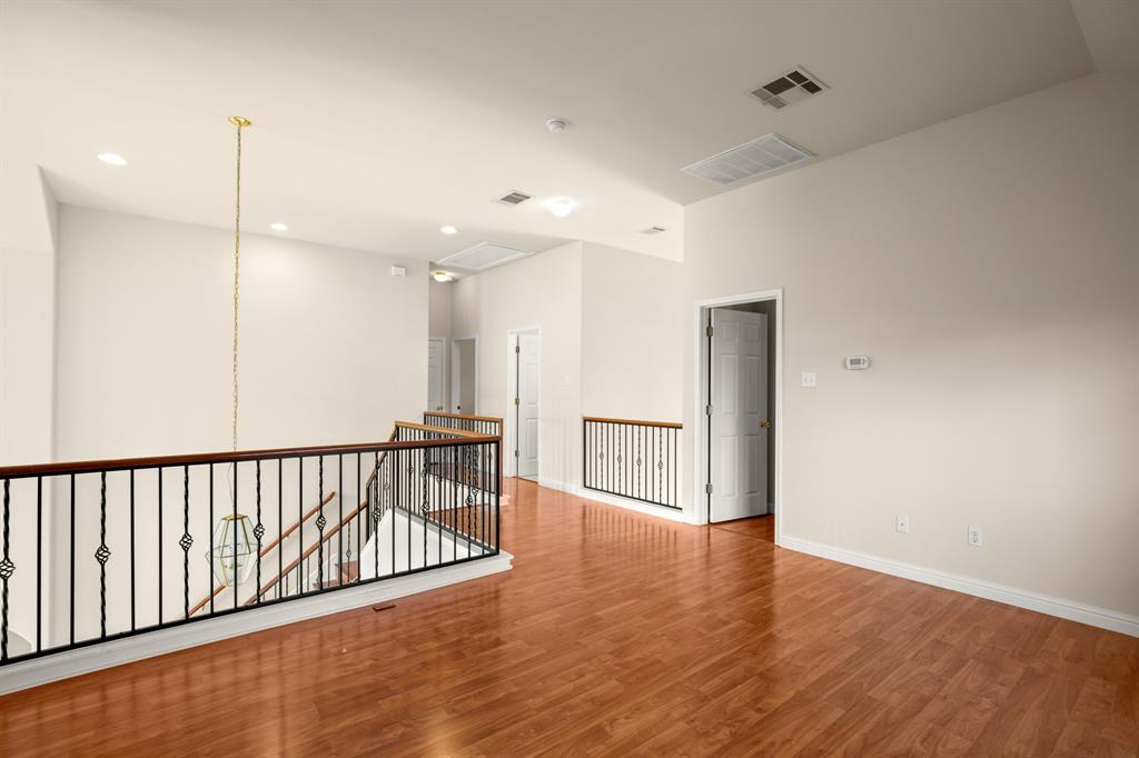 10105 Wind Cave Trail Austin, TX 78747 - Photo 15 of 23 Spacious upper-level landing featuring wood-finish flooring, wrought iron railings with wood handrails, recessed lighting, and a prominent hanging light fixture