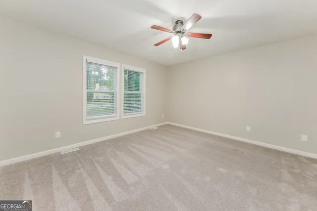 an empty room with ceiling fan and window