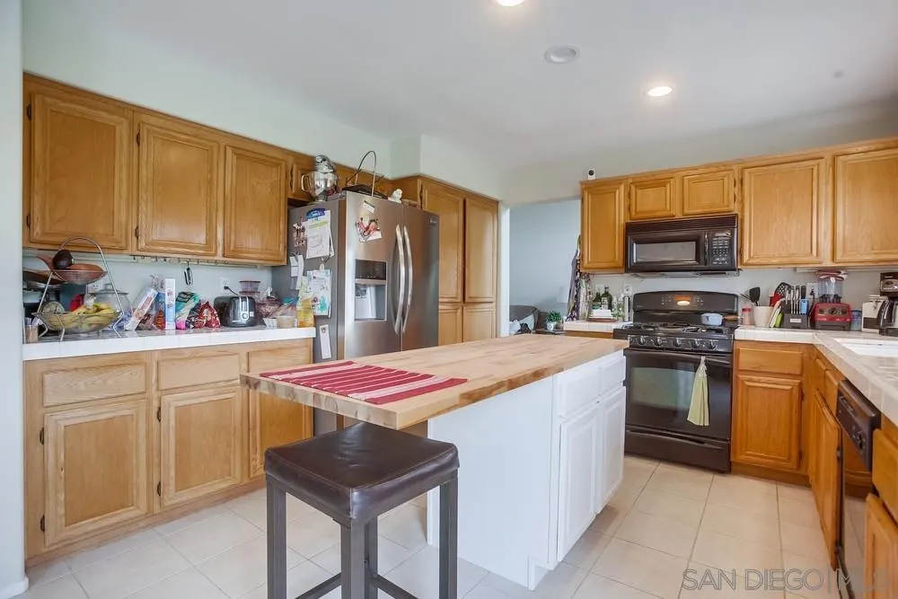 498 Shadow Tree Drive Oceanside, CA 92058 - Photo 13 of 42 a kitchen with stainless steel appliances granite countertop a sink stove and refrigerator