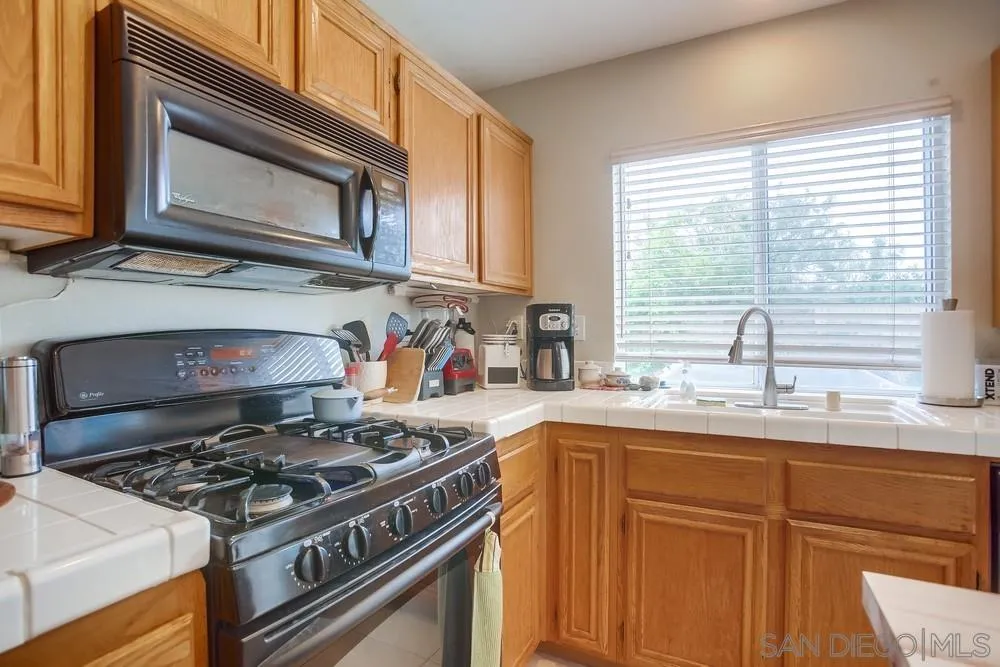 498 Shadow Tree Drive Oceanside, CA 92058 - Photo 14 of 42 a kitchen with stainless steel appliances granite countertop a sink stove and cabinets