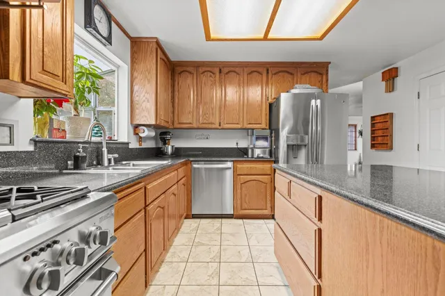 a large kitchen with stainless steel appliances granite countertop a stove a sink and a microwave