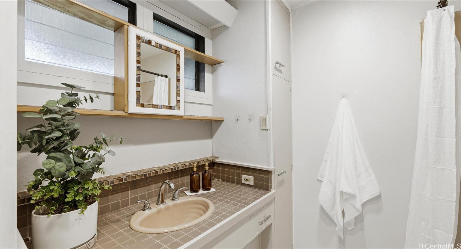 91-779 Fort Weaver Road Ewa Beach, HI 96706 - Photo 15 of 25 Private en-suite bathroom featuring a tiled vanity, built-in mirror, and convenient cabinet storage.