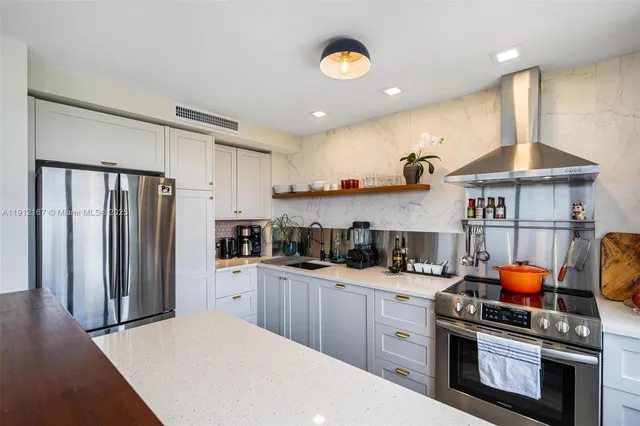 a kitchen with stainless steel appliances granite countertop a sink a stove a refrigerator cabinets and wooden floor