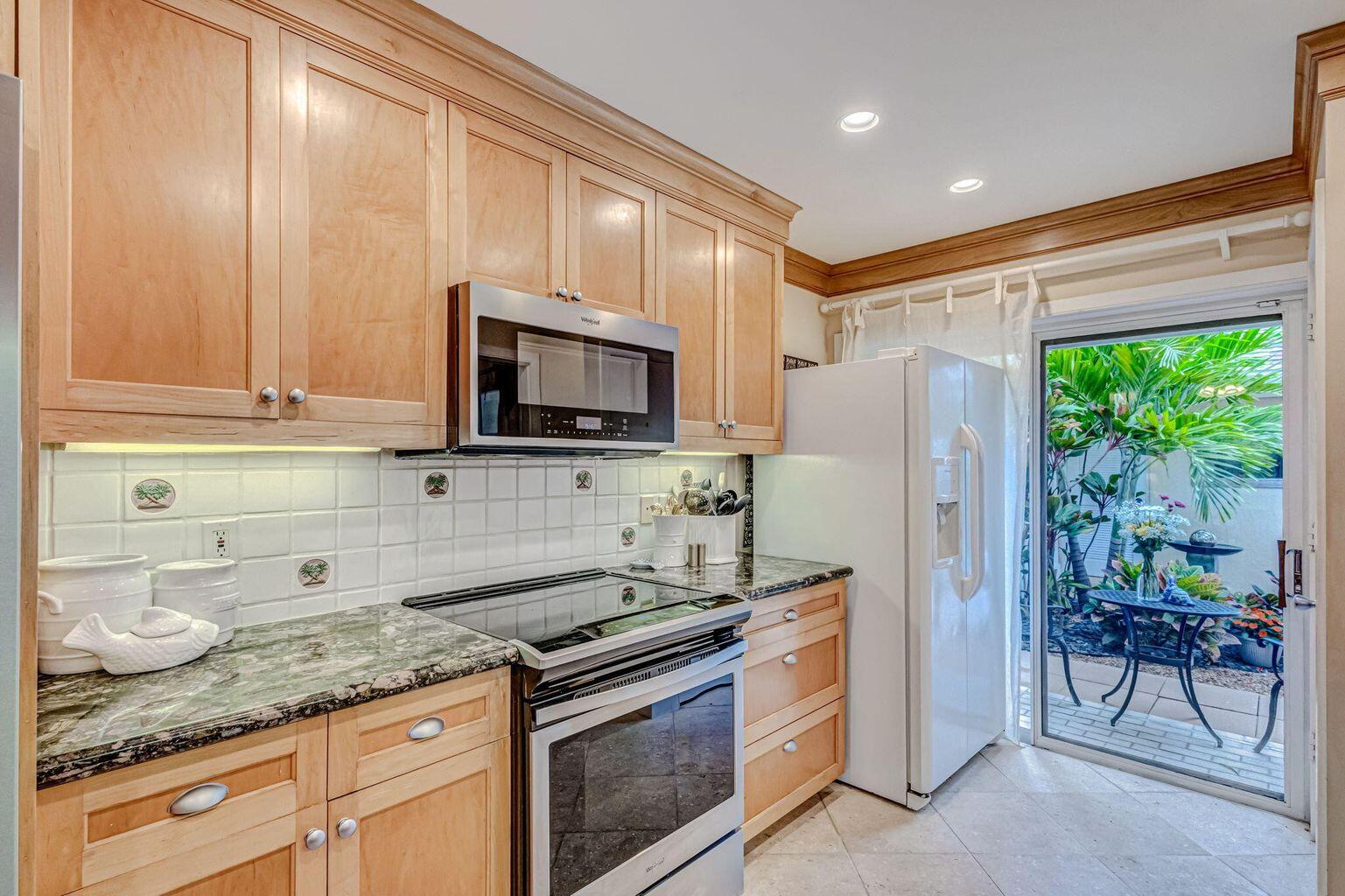 3667 Cape Pointe Circle Jupiter, FL 33477 - Photo 12 of 37 a kitchen with stainless steel appliances granite countertop a stove a refrigerator and a microwave