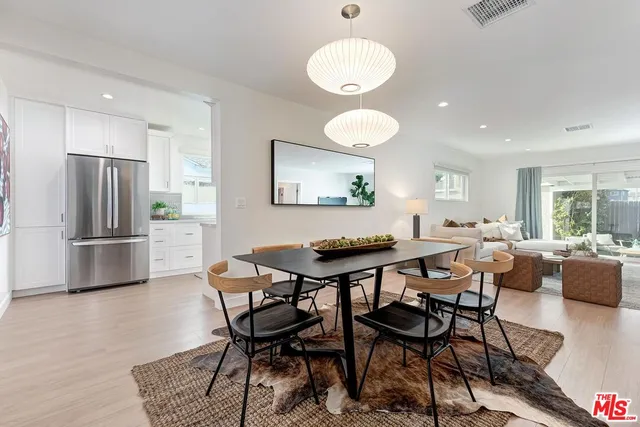 a kitchen with stainless steel appliances a dining table chairs and a refrigerator