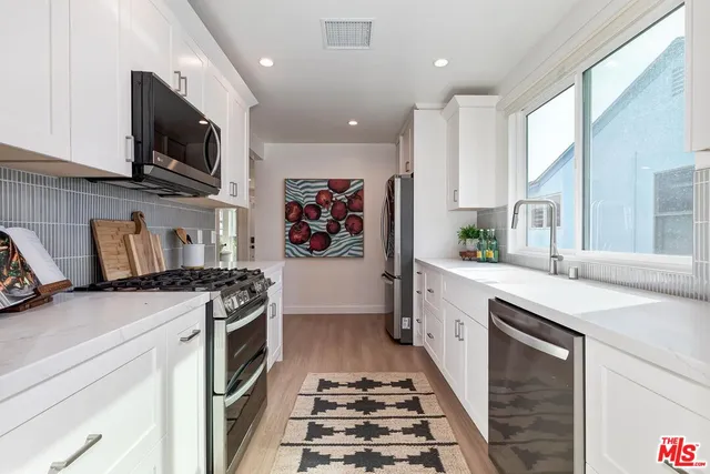 a kitchen with stainless steel appliances granite countertop a stove a sink and a microwave