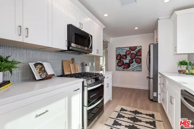 a kitchen with stainless steel appliances granite countertop a stove a sink and a microwave