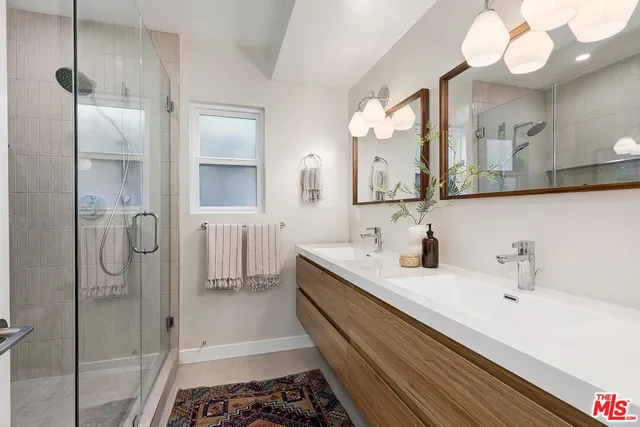 a bathroom with a double vanity sink mirror and shower