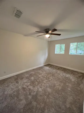 an empty room with windows and chandelier fan
