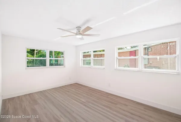 an empty room with wooden floor and windows
