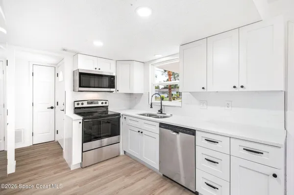 a kitchen with white cabinets and appliances