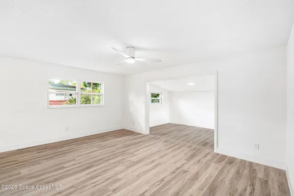 an empty room with wooden floor and windows